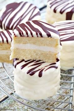 several desserts with white frosting and chocolate drizzled on them