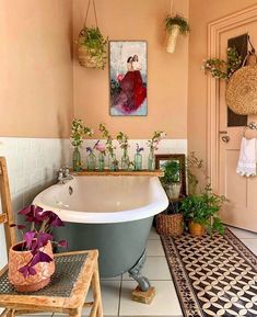 a bath tub sitting next to a table with flowers on it and potted plants