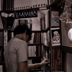 a man standing in front of a book shelf filled with books