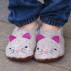 a child's feet wearing slippers with a cat face on them and blue jeans