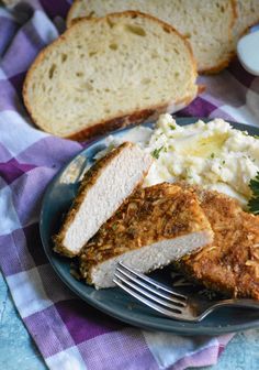 a plate with bread, mashed potatoes and meat on it next to a fork