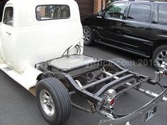 an old white truck is parked next to another black car in a parking lot with other cars