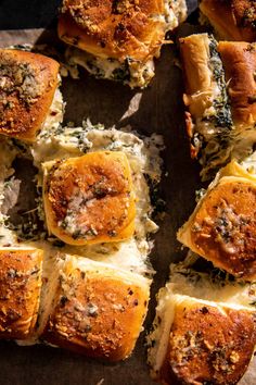 several pieces of bread with cheese and spinach on top, cut in half to look like sliders