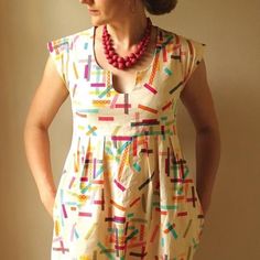 a woman standing in front of a wall wearing a dress with colorful sprinkles on it