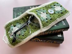 a pair of glasses sitting on top of a book with a crocheted cover