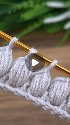 the video shows how to crochet in two rows with yarn and gold knitting needles