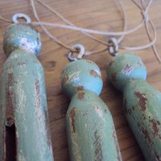 three green wooden pegs sitting on top of a wooden floor next to a string