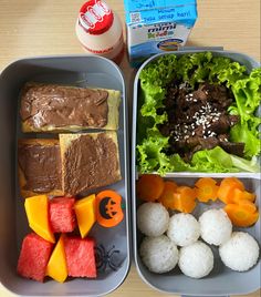 two plastic trays filled with food on top of a wooden table next to a carton of milk