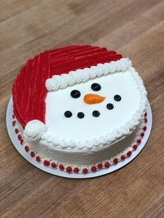 there is a cake decorated like a snowman on top of a wooden table with red and white frosting