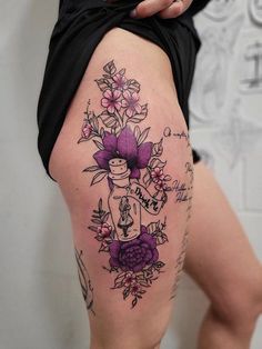 a woman's thigh with tattoos and flowers on it