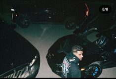 a man standing next to a black sports car