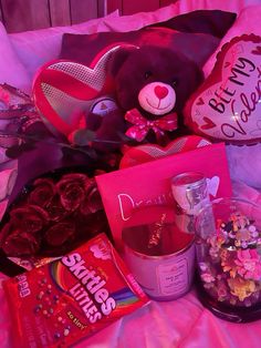 a teddy bear sitting on top of a bed next to valentine's day treats