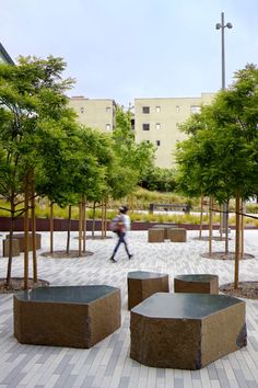 a man walking through a park with benches and trees