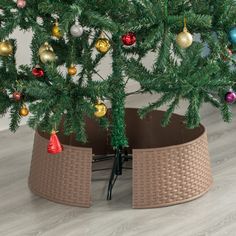 a small christmas tree in a basket with ornaments on it