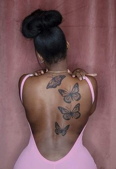 the back of a woman's body with butterflies tattooed on her upper and lower back