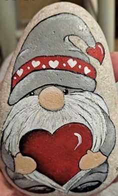 a hand holding a painted rock with a heart on it