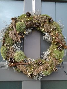 a wreath with pine cones, moss and lights