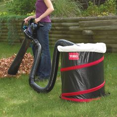 a woman is using a vacuum to clean the grass