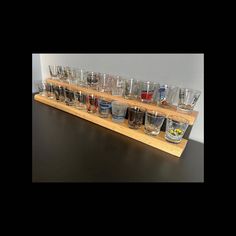 many glasses are lined up on a wooden shelf