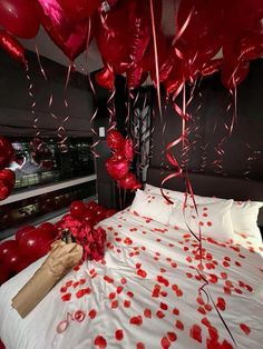 red balloons and streamers fill the air above a bed in a room decorated for valentine's day