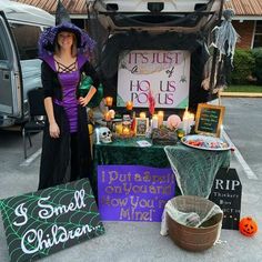 a woman dressed as a witch standing next to a table with halloween decorations on it