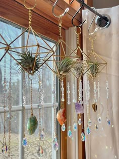 three air plants hanging from the ceiling in front of a window with beads and chains attached to them