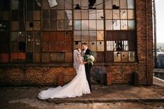 a bride and groom standing in front of an old building with broken glass on the windows