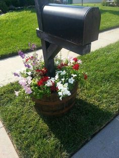 a mailbox with flowers in it sitting on the grass