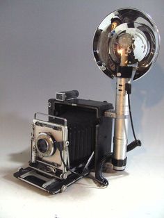 an old fashioned camera sitting on top of a tripod next to a vintage camera