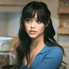 a woman with long black hair is posing for a photo in front of an oven