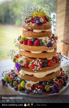 a multi layer cake with fresh fruit and flowers on top