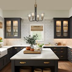 a kitchen with black cabinets and white counter tops, an island in the middle is filled with dishes