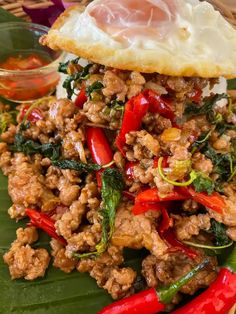 a plate topped with meat and veggies on top of a banana leaf