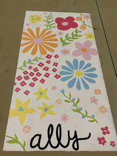 a white rug with flowers and the word ally painted on it's side in black ink