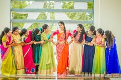 a group of women standing next to each other in front of a window with their arms around each other