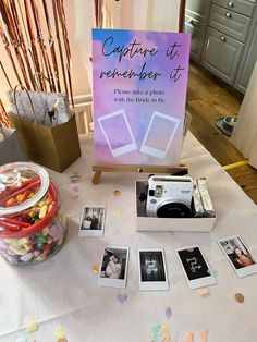 a table topped with pictures and a camera next to a jar filled with candies