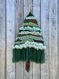 a knitted christmas tree hanging on a wooden fence