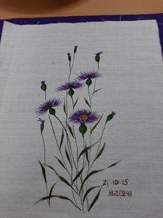 some purple flowers are on a white cloth