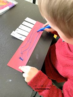 a young boy is drawing on a piece of paper