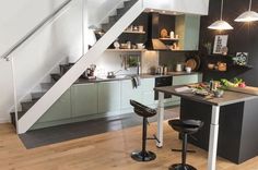 an open kitchen with stairs leading up to the upper floor and dining area in front of it