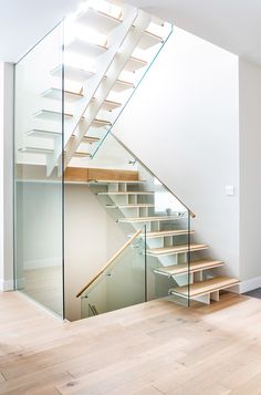 an empty staircase with glass railing and wooden steps