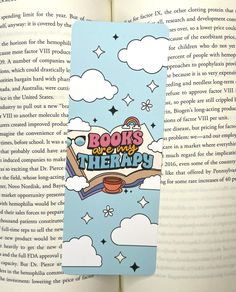 a bookmark with the title books are my therapy written on it in front of an open book