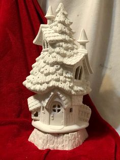 a white ceramic christmas tree house sitting on top of a red blanket