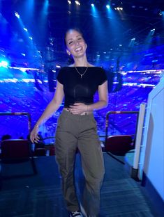 a woman standing in front of a stage with her hands on her hips and smiling at the camera