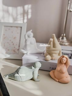 three small figurines sitting on top of a table next to books and pictures