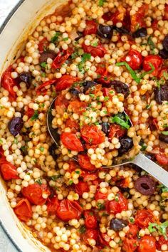 a pot filled with corn, tomatoes and olives