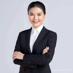 a woman in a black suit and white shirt is smiling at the camera with her arms crossed