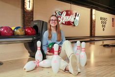 a woman is sitting on the floor with her bowling balls