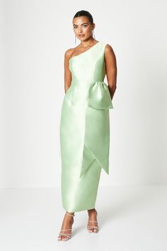 a woman is wearing a green dress with one shoulder and bow at the waist,