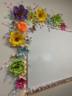 a mirror that has flowers on it and lights around the edges in front of it